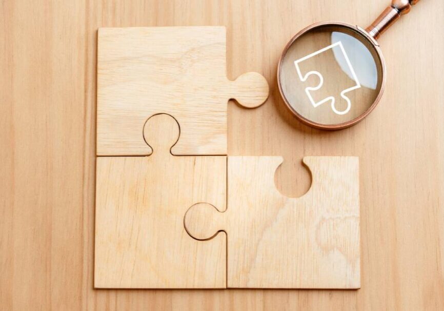 Wooden puzzle pieces with magnifying glass.